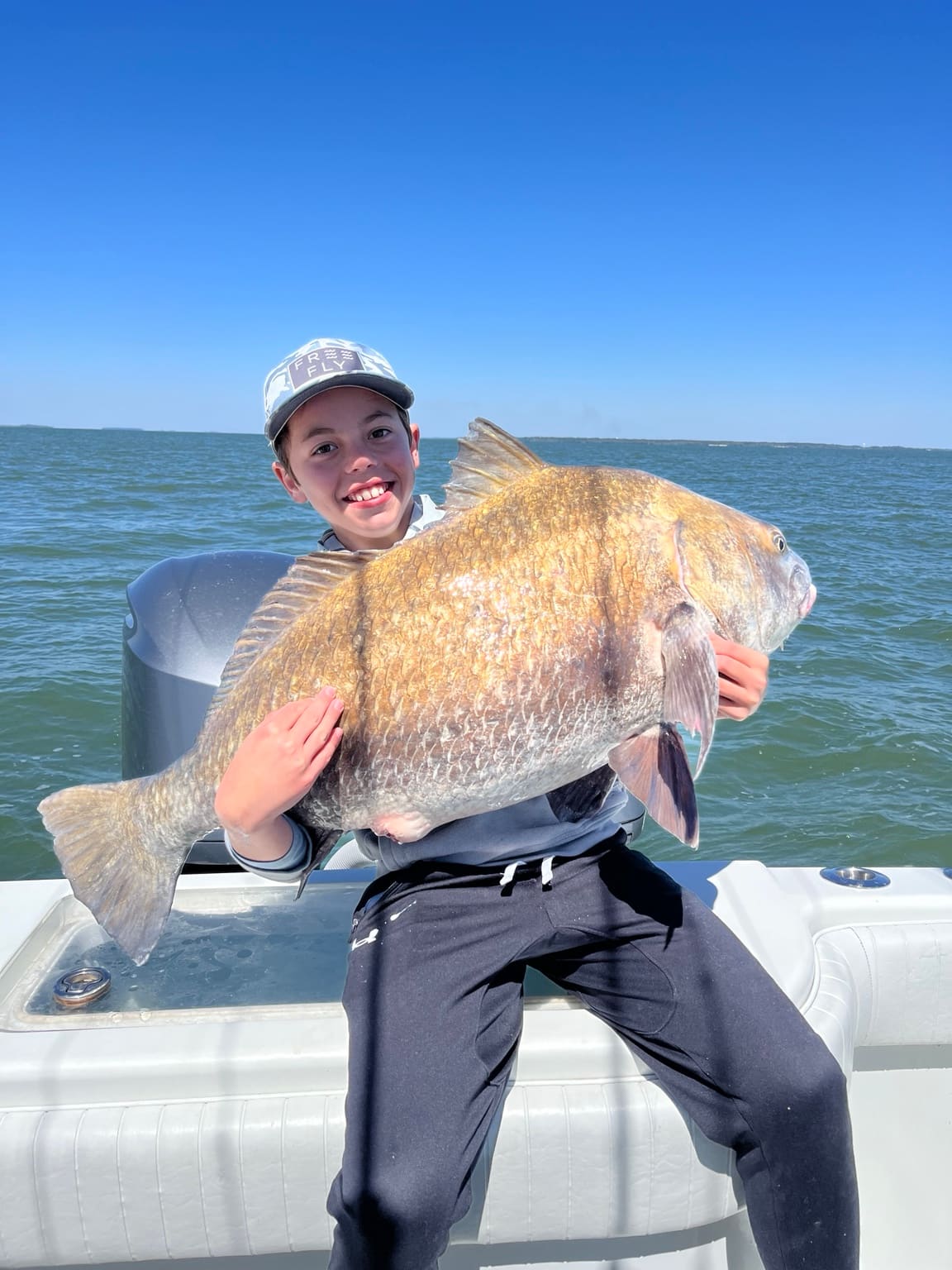 A young angler holding a large black drum on a Southern Hook charter